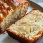 A close-up view of moist and fluffy Cottage Cheese Banana Bread with a golden-brown crust, served on a white plate.