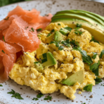 Close-up of a high-protein breakfast with scrambled eggs, avocado slices, and smoked salmon on whole-grain toast