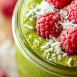 Close-up of matcha chia pudding with raspberries and coconut.